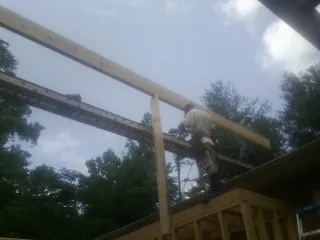 Carpenter setting a ridge beam over a new addition frame — Ice Dam Removal by Roofing Brothers in Mack
