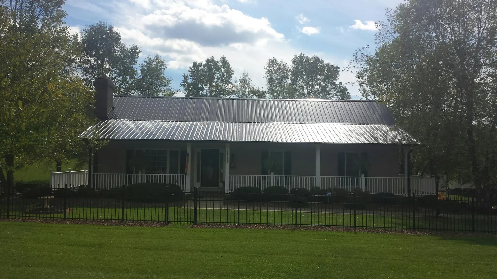 Gray metal roof on a brick ranch with a full width front porch — Gutter Guard Installation work by our crew in Mack